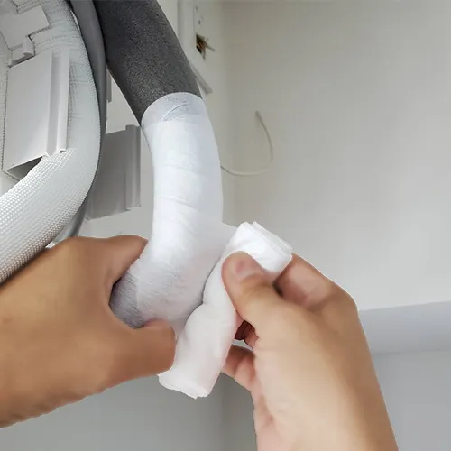 ドレンホースに断熱材を巻く作業員