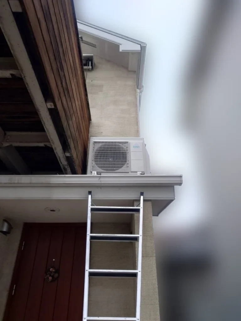 梯子作業。戸建て物件の2階部分での室外機屋根置き作業。室外機設置完了